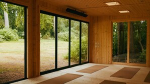 Ein Zimmer mit großen Fenstern, Holzboden und Yogamatten.