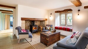 A cozy living room with a stone fireplace, comfortable seating, and a large window with a view. - Threshing Mill - Four Bedroom Villa, Sleeps 8 (Marshfield)