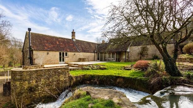 A stone building with a tiled roof, a small stream, and a grassy area. - Threshing Mill - Four Bedroom Villa, Sleeps 8 (Marshfield)