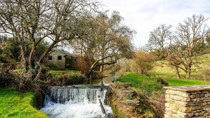 A rustic stone bridge over a flowing stream, surrounded by lush greenery and trees. - Threshing Mill - Four Bedroom Villa, Sleeps 8 (Marshfield)