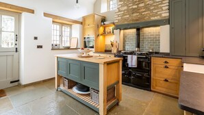 A kitchen with a central island, a stone wall, and a large oven. - Threshing Mill - Four Bedroom Villa, Sleeps 8 (Marshfield)