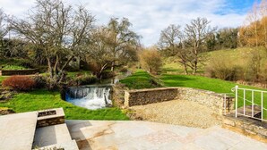 A stone pathway leading to a small waterfall in a park with grassy areas and trees. - Threshing Mill - Four Bedroom Villa, Sleeps 8 (Marshfield)