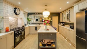 A modern kitchen with a central island, stainless steel appliances, and a decorative chandelier.