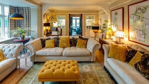 A spacious living room with a large sofa, a matching ottoman, and a dining area with a table and chairs.