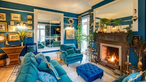 A living room with a fireplace, blue sofas, and a large window.