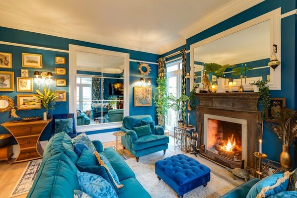 A living room with a fireplace, blue sofas, and a large window.