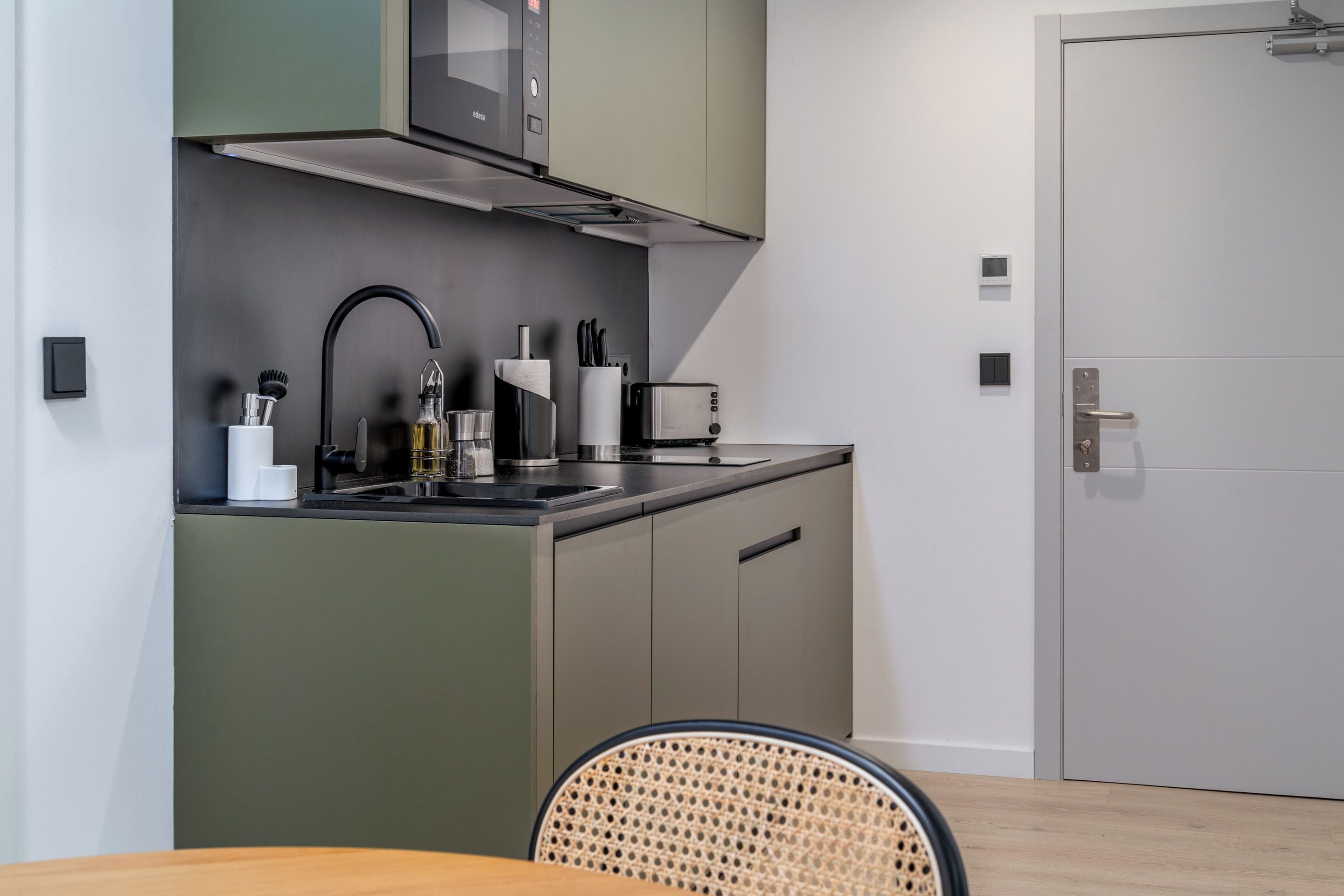 A modern kitchen with a microwave, toaster, sink, and cabinets.