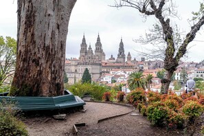 A park with a large tree, a bench, and a view of a historic building with multiple towers. - Limehome Santiago de Compostela (Santiago de Compostela)