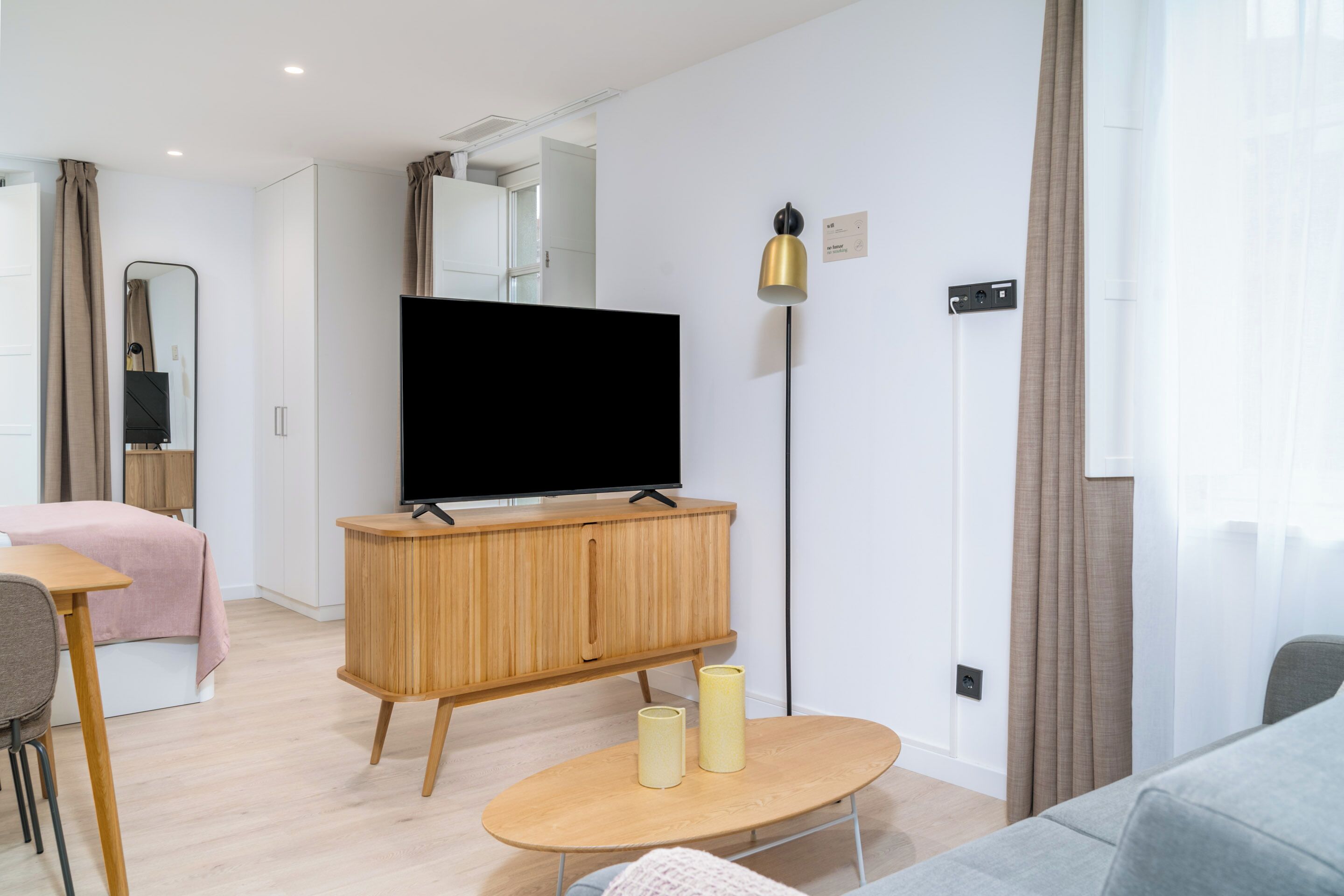 A modern living room with a flat-screen TV, wooden furniture, and a minimalist design.