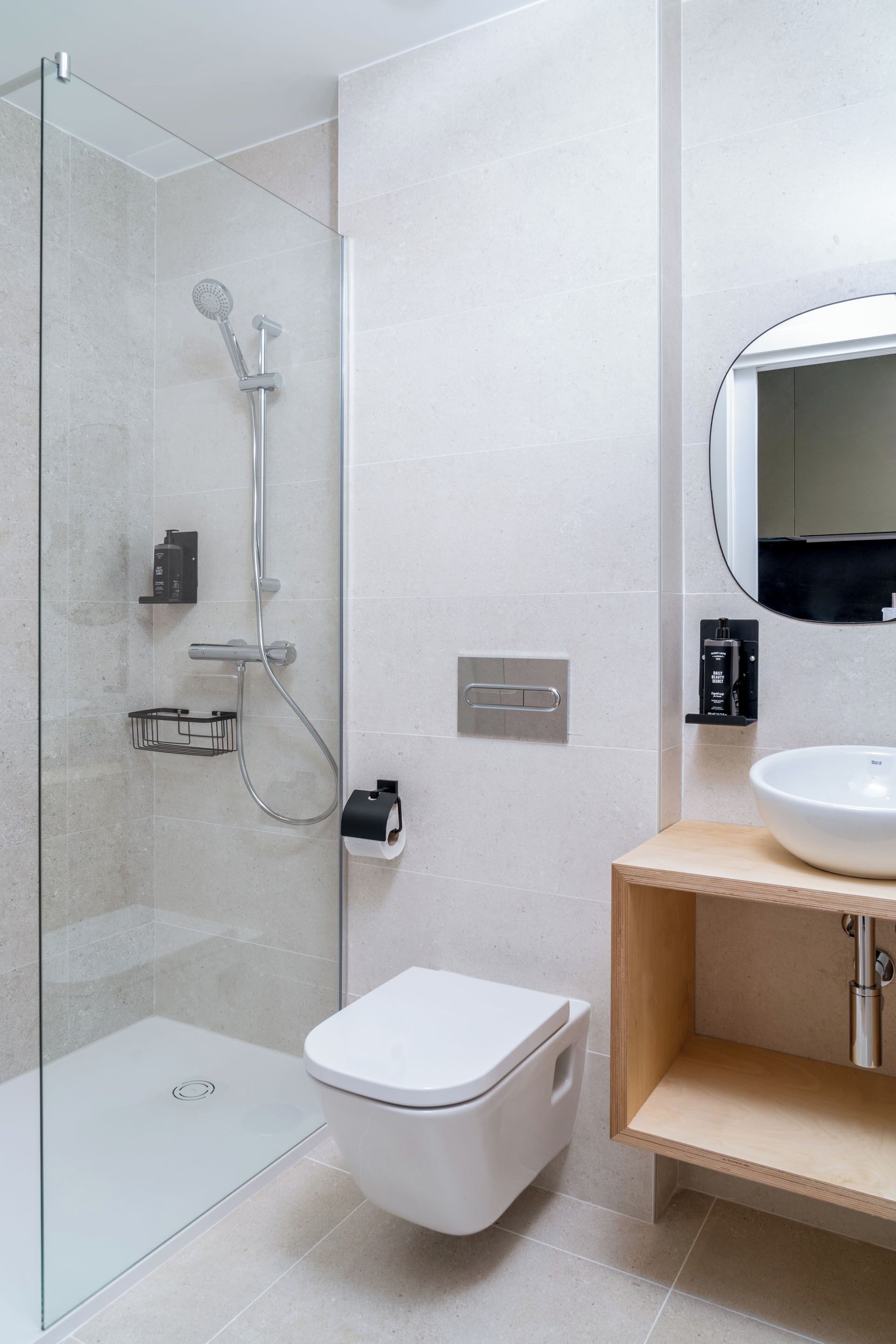 Une salle de bain moderne avec une douche à parois de verre, des toilettes blanches, un meuble-lavabo en bois et un miroir.
