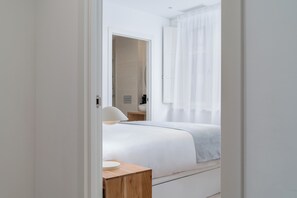 A modern hotel room with a neatly made bed, a bedside table, and a bathroom visible through an open door. - Limehome Santiago de Compostela (Santiago de Compostela)