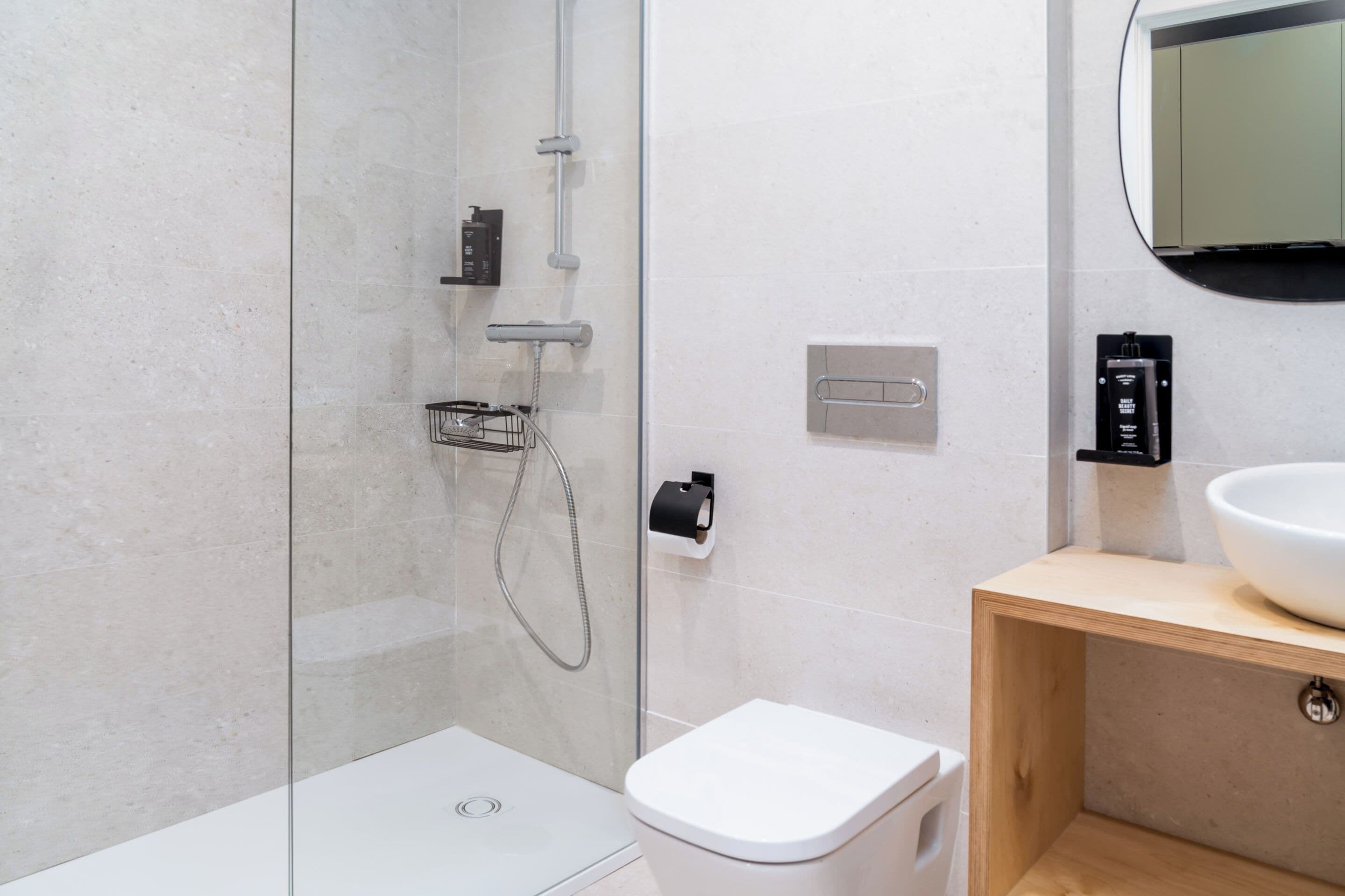 A modern bathroom with a glass-enclosed shower, a white toilet, and a wooden vanity with a white sink.