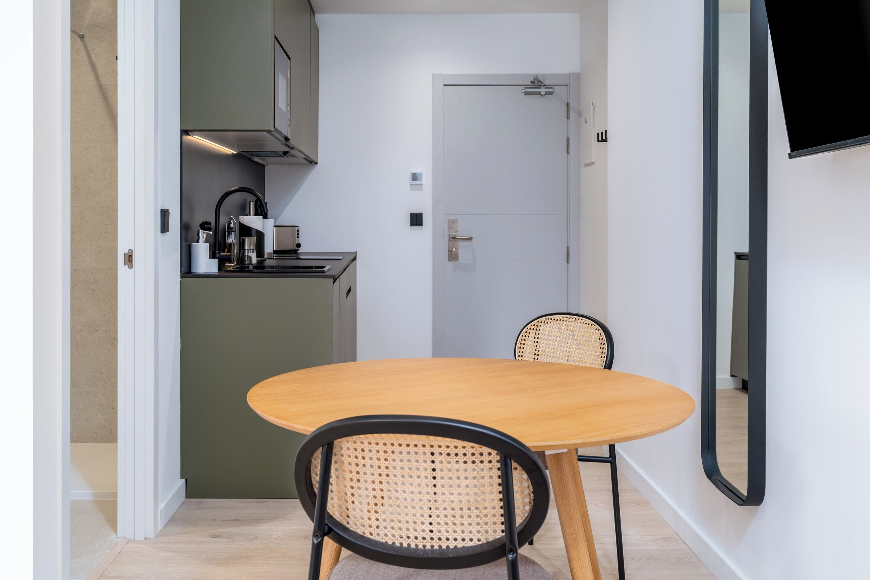 A compact kitchen with a dining area, including a table and chairs, and a door leading to another room.