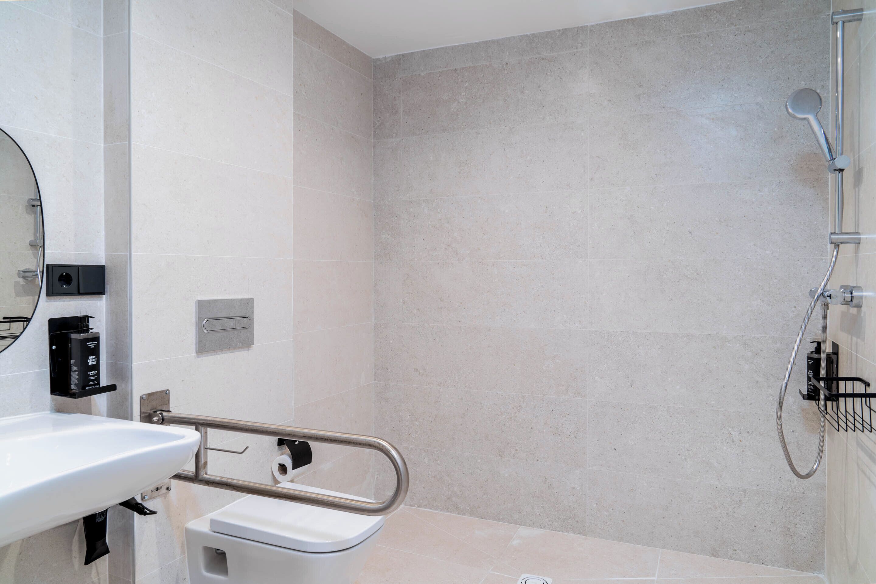 Un baño moderno con lavamanos, inodoro y zona de ducha blancos.