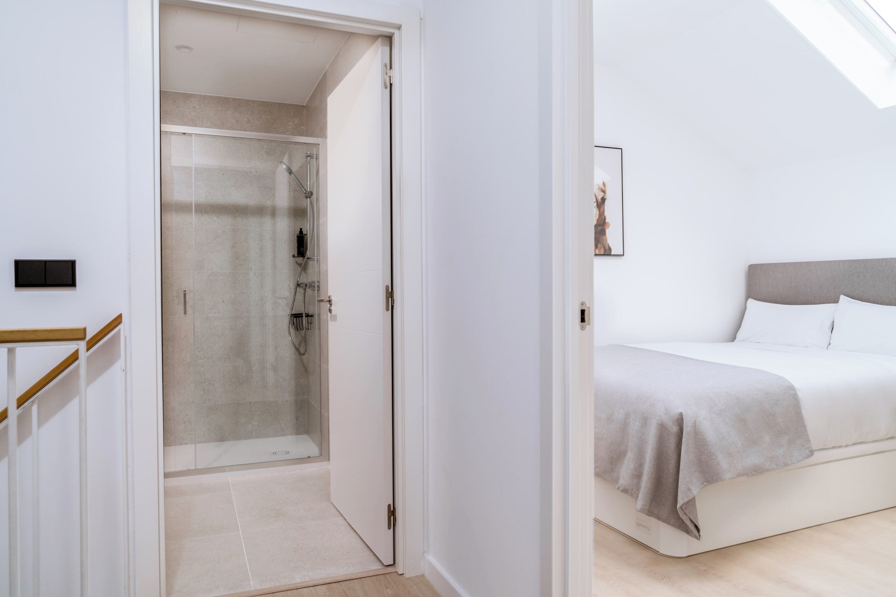 A modern bedroom with a bed, a bedside table, and a shower area.