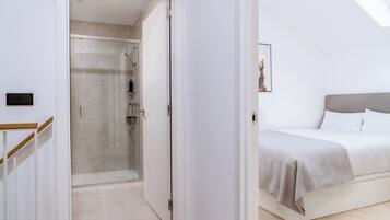 Un dormitorio moderno con cama, mesita de noche y zona de ducha.