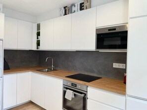 A modern kitchen with white cabinets, a wooden countertop, a stainless steel sink, a built-in oven, and a microwave. - Cosy Bilbao City Center Apartment - 2BR (Bilbao)
