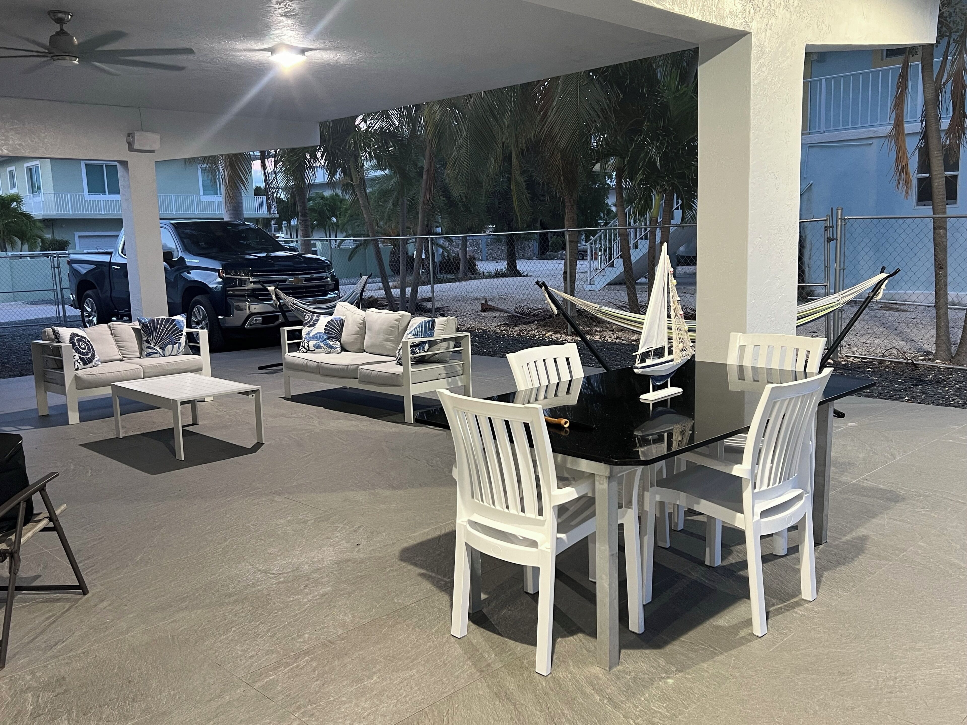 Eine Terrasse im Freien mit Esstisch und Stühlen, einer Hängematte und einem Modell eines Segelboots.