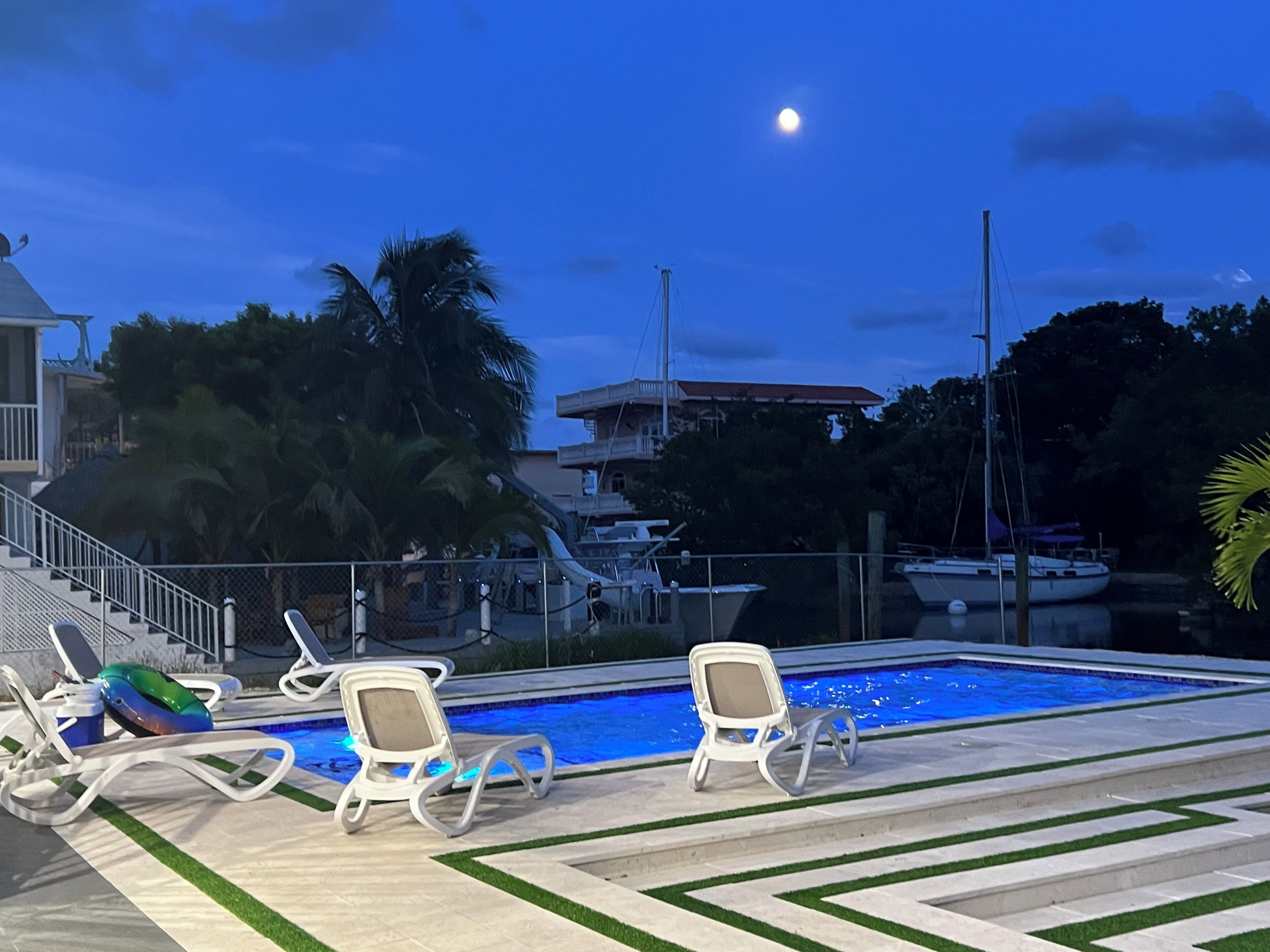 Un espace piscine avec des chaises longues et une vue sur l’océan au crépuscule.