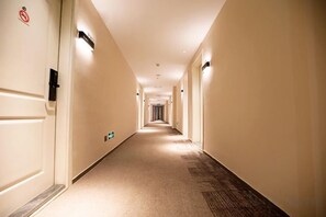 A hotel hallway with doors on both sides, a carpeted floor, and a sign indicating a no-smoking area. - Songguo Hotel (Wenhua Road) (Zhengzhou)