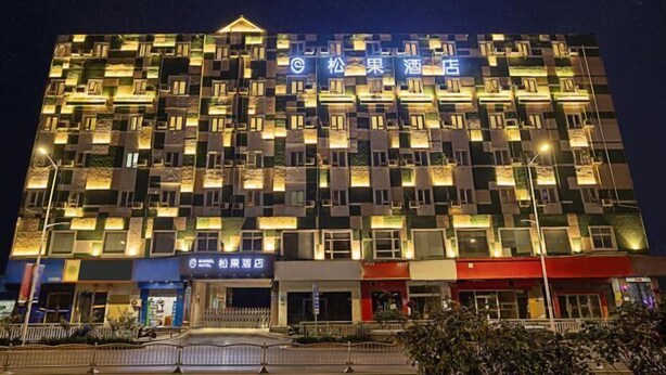 A multi-story hotel with a distinctive facade featuring numerous illuminated windows and balconies. - Songguo Hotel (Wenhua Road) (Zhengzhou)