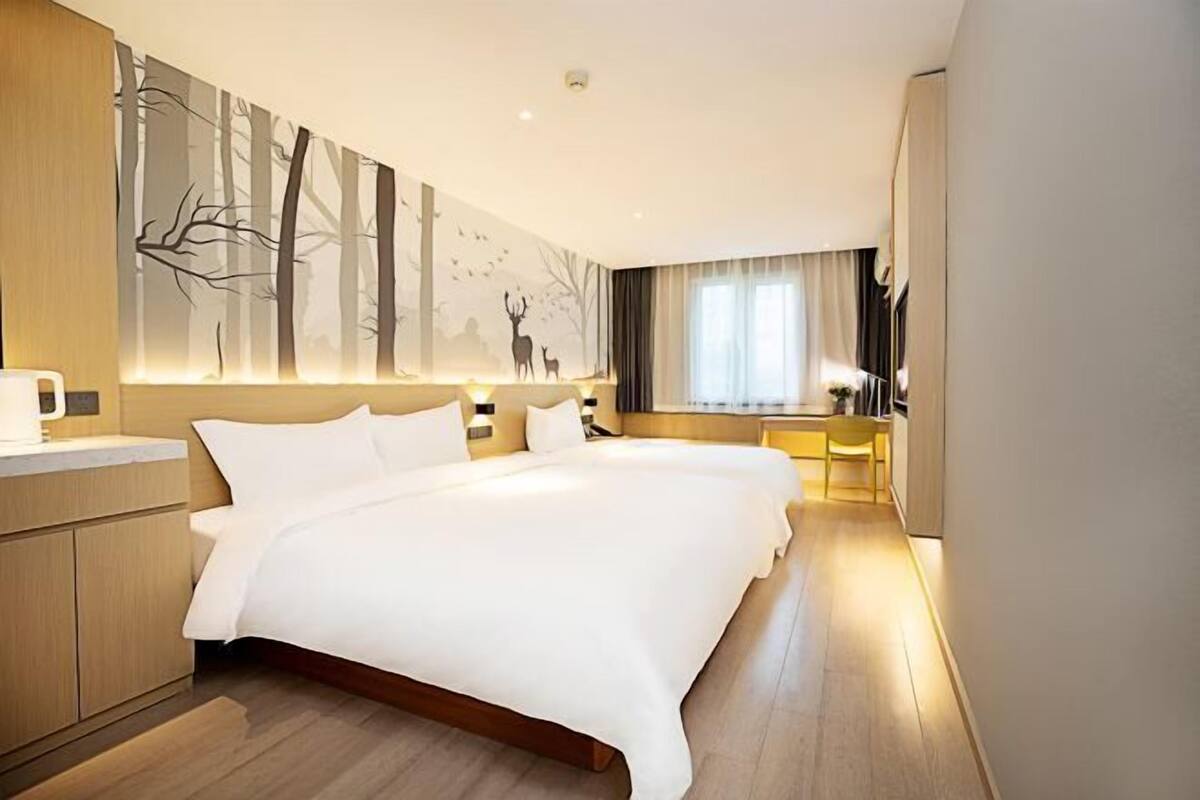 Una habitación de hotel moderna con una cama grande, un escritorio y un mural en la pared.