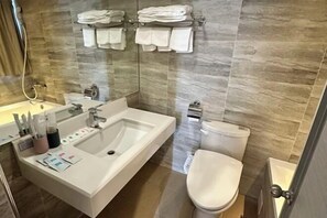 A modern bathroom with a large sink, toilet, and shower area.