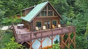 Uma cabana de madeira com varanda, rodeada por uma floresta densa.