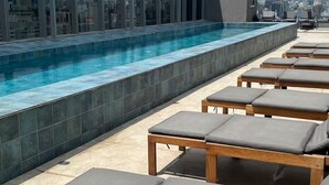 A rooftop pool area with lounge chairs and a city view. - Studio na avenida 9 de julho (São Paulo)