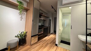 A modern kitchen with wooden cabinets, a built-in oven, and a microwave. - Studio na avenida 9 de julho (São Paulo)