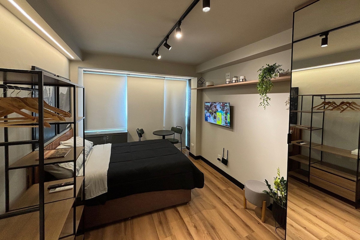 Una habitación de hotel moderna con cama, televisión, escritorio y armario.