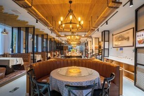 A restaurant with a central round table, booths, and a wooden ceiling. - Wuyuan Bohaiyuan Hot Spring Hotel (Eryuan)