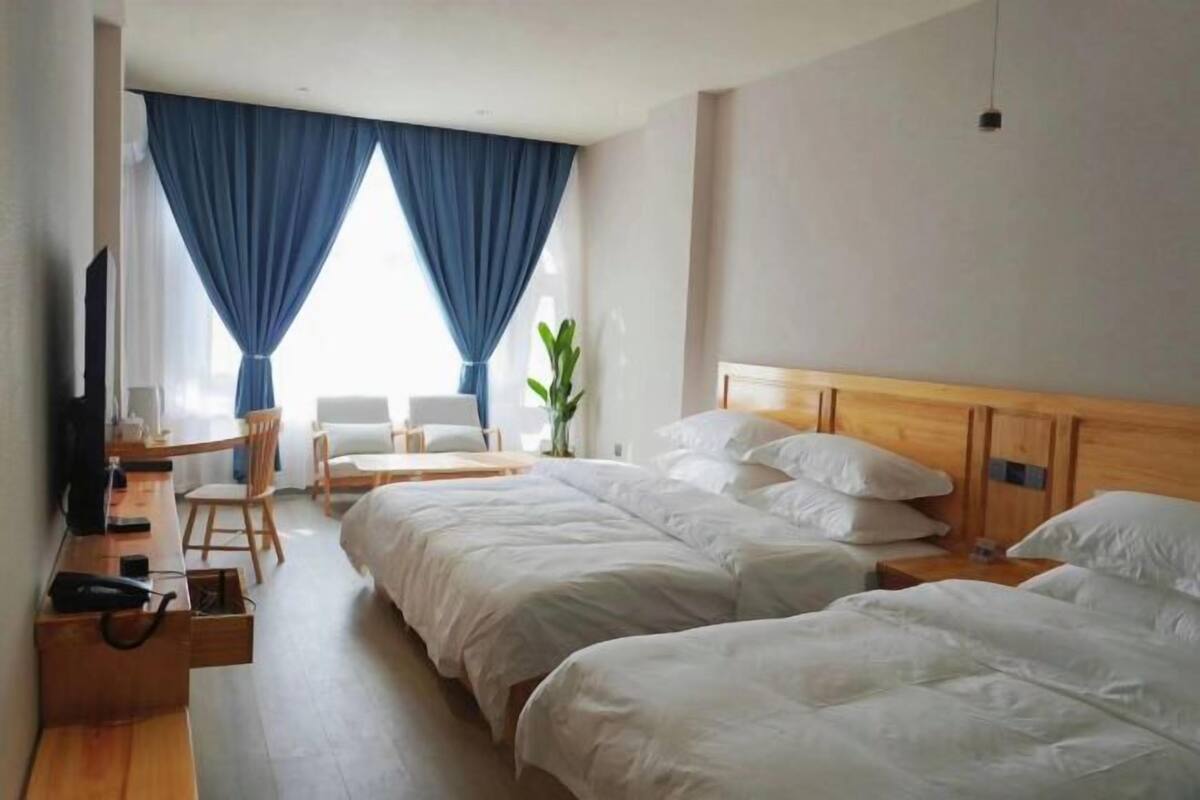 Ein Hotelzimmer mit zwei Betten, einem Schreibtisch, einem Sessel, einem Fernseher und einer Pflanze.