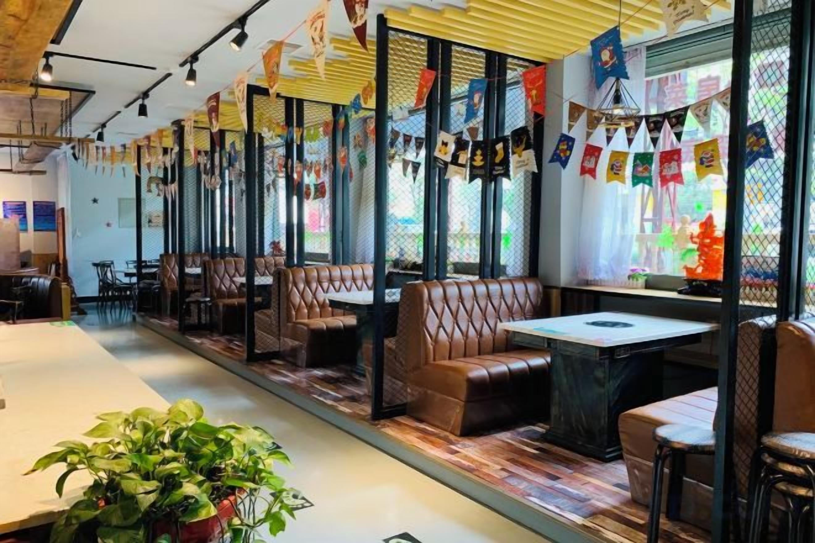 A restaurant with booths and tables, a potted plant, and a window with a view.