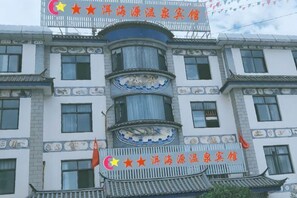 Un immeuble à plusieurs étages doté d’éléments architecturaux traditionnels, notamment un balcon incurvé et des carreaux décoratifs.