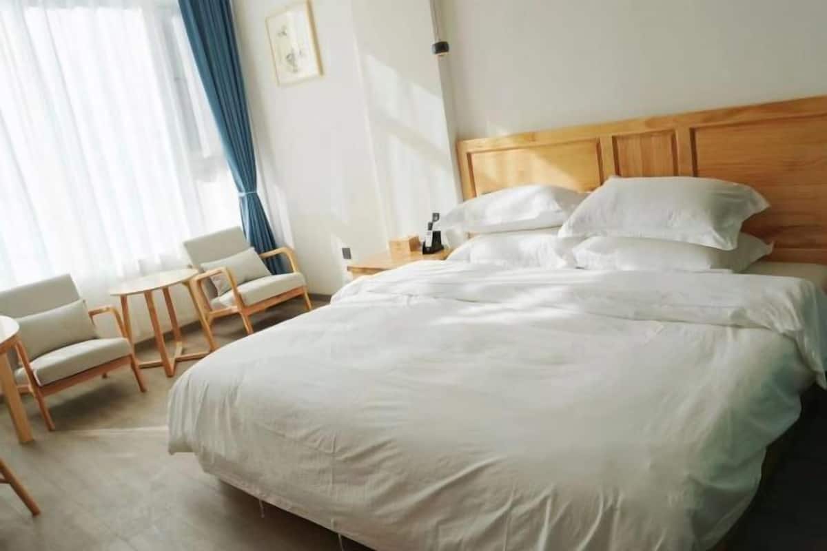 Ein Hotelzimmer mit Bett, kleinem Tisch, zwei Stühlen und einem Nachttisch.