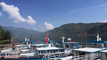 A marina with several boats docked, a clear sky, and mountains in the background.