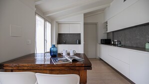 Eine moderne Küche mit weißen Schränken, einem Holztisch und einer blauen Vase.