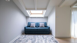 Une pièce dotée d’une lucarne, d’un canapé bleu agrémenté de coussins et d’un tapis à motifs.