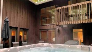 A hot tub in a wooden cabin with a balcony and large windows. - Family chalet and SPA near Mont Orford (Orford)