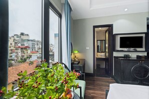 A hotel room with a large window, a television, a small table with a lamp, and a view of the cityscape. - 22land 52 Ngo Huyen Hotel & Spa (Hanoi)