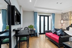 A modern living room with a sofa, dining table, and TV. - 22land 52 Ngo Huyen Hotel & Spa (Hanoi)