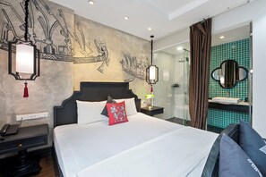 A hotel room with a large bed, a nightstand with a phone, a wall with decorative art, a bathroom with a mirror, and a shower area. - 22land 52 Ngo Huyen Hotel & Spa (Hanoi)