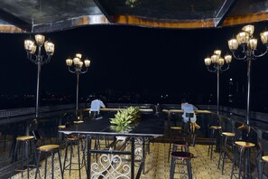 An outdoor dining area with tables and chairs, a potted plant, and decorative lighting. - 22land 52 Ngo Huyen Hotel & Spa (Hanoi)