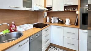 Una cocina moderna con armarios blancos, un lavamanos de acero inoxidable y un horno empotrado.