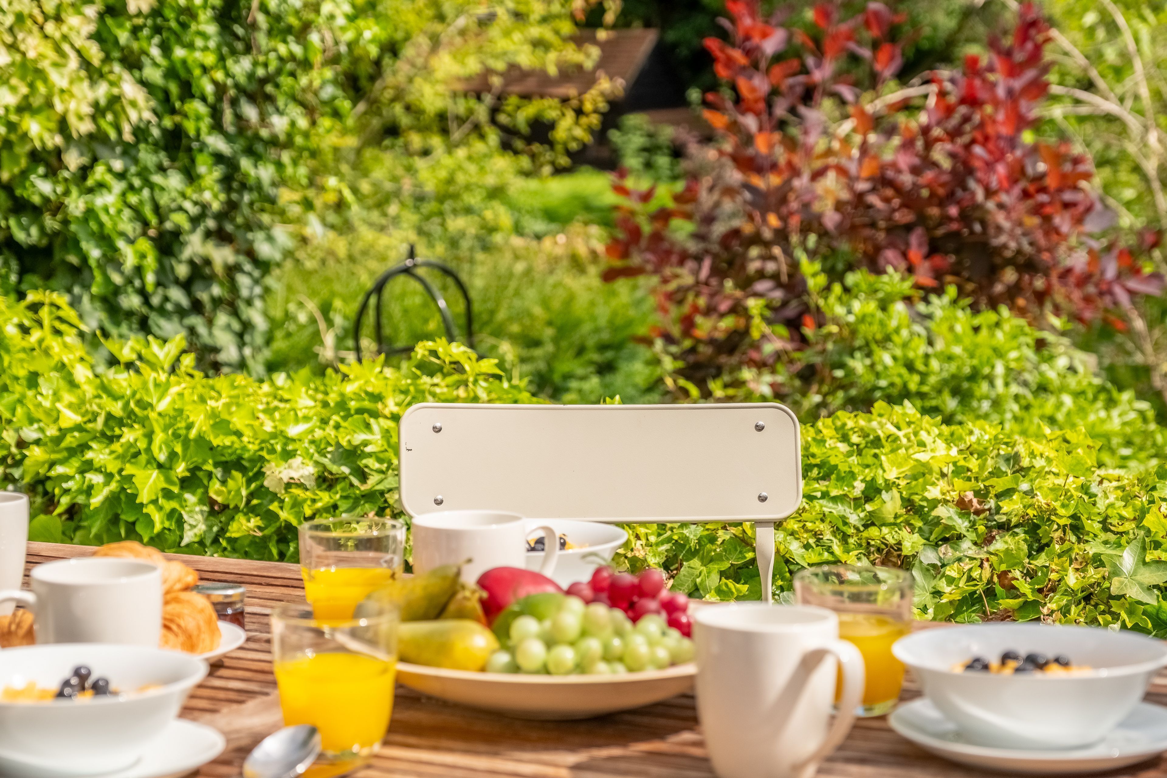 Une table de petit-déjeuner installée à l’extérieur, avec une variété de fruits, de viennoiseries et de boissons.