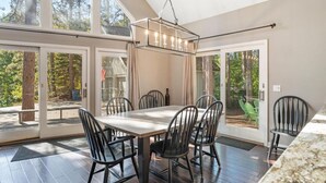 Un vaste espace dédié à la salle à manger, avec une grande table et des chaises, de grandes fenêtres et une vue sur l’extérieur.