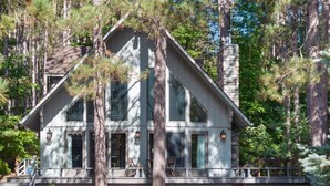 Une cabane à deux étages avec un porche, entourée de grands arbres.