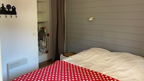 A bedroom with a bed, a radiator, a closet with hanging items, and a window with curtains. - Apparemment sur les Pistes de ski Avec Piscine Risoul1850 Hautes Alpes (Risoul)