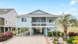 A two-story house with a covered porch and a staircase leading to the upper floor. - Updated Sunset Beach home w/ a 2-minute walk to the beach.  Parking for 5 cars. (Sunset Beach)